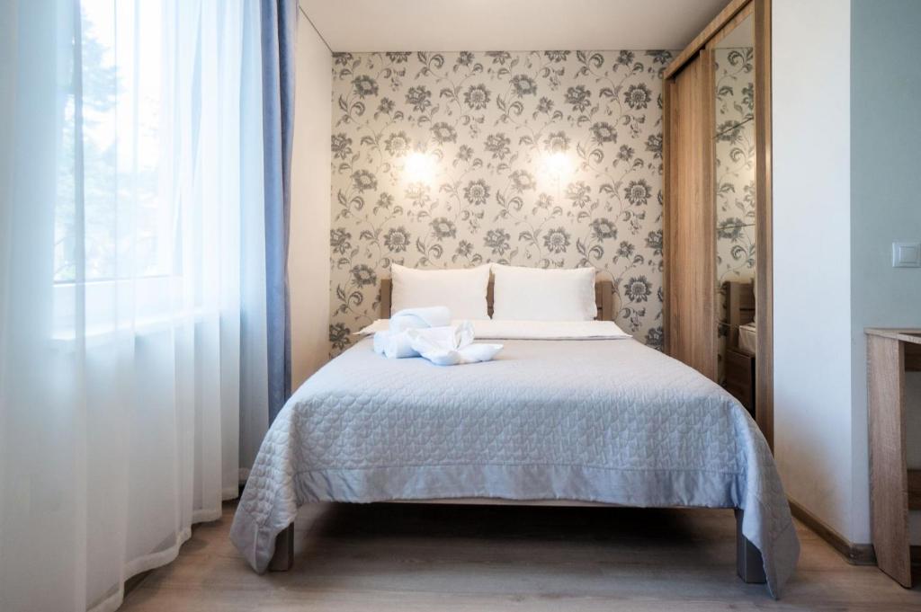 - une chambre avec un lit et un mur orné de papier peint floral dans l'établissement Šarkutė, à Palanga