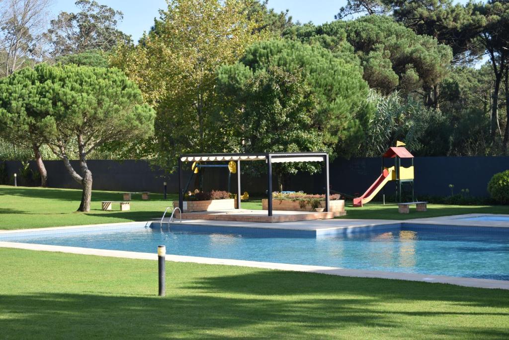 a swimming pool with a slide and a playground at Parkofir in Fão