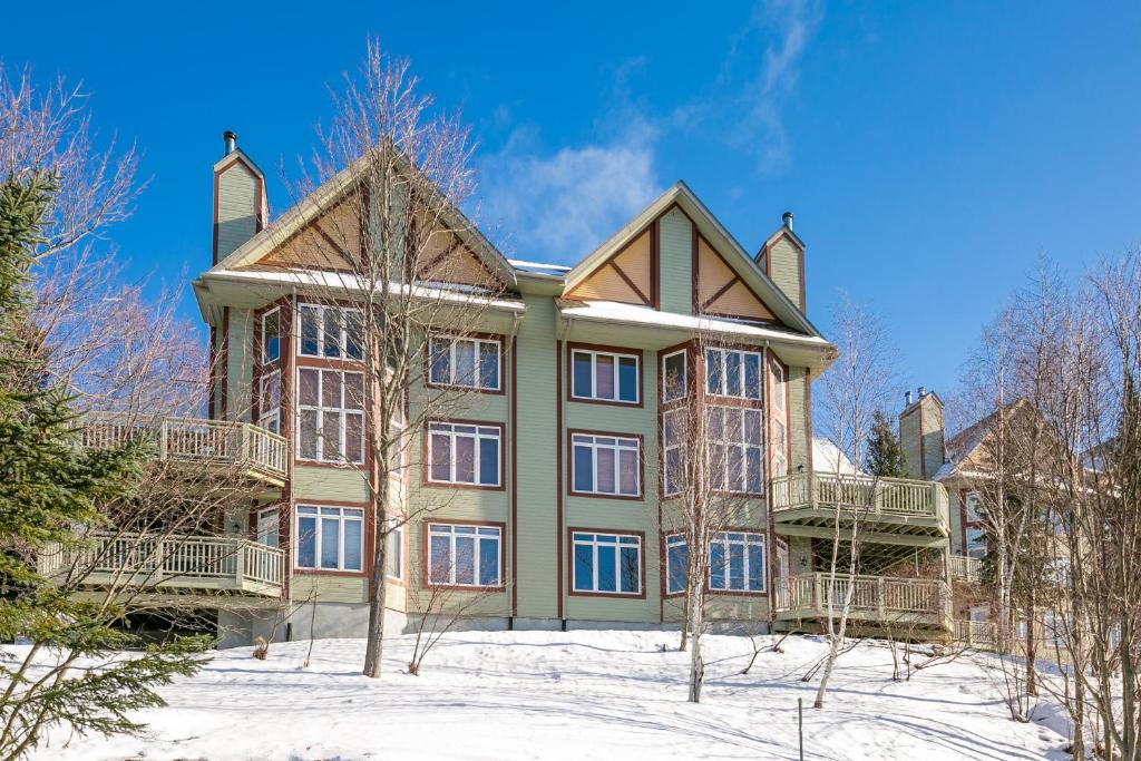 a large house with snow in front of it at Le Chalumeau by Chez Tremblant in Mont-Tremblant