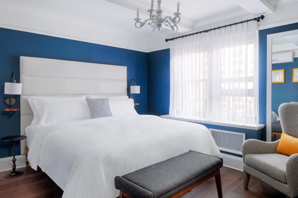 a white bed sitting in a bedroom next to a window at voco The Franklin New York, an IHG Hotel in New York