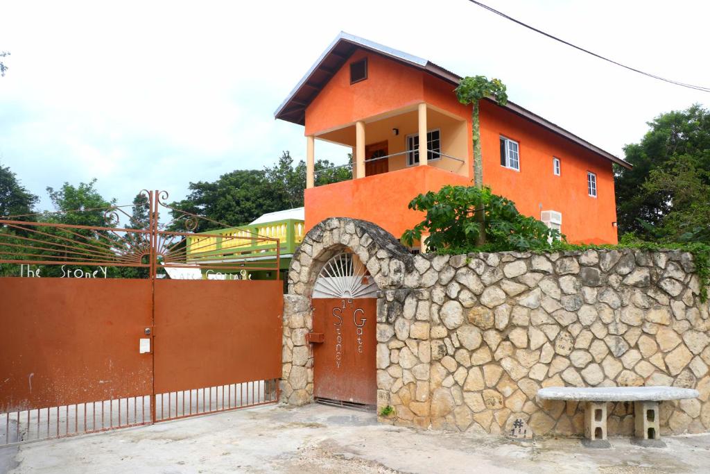 a orange building with a stone wall and a gate at Stoney Gate Cottages in Negril