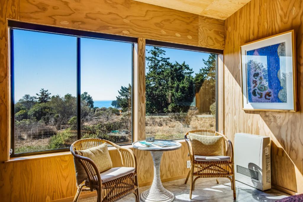Habitación con mesa, sillas y ventanas grandes. en Wild Meadow, en Sea Ranch