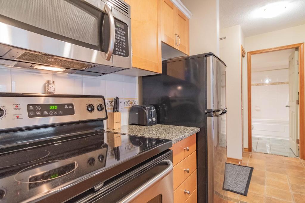 a kitchen with a stove and a microwave at The Aspens by Outpost Whistler in Whistler