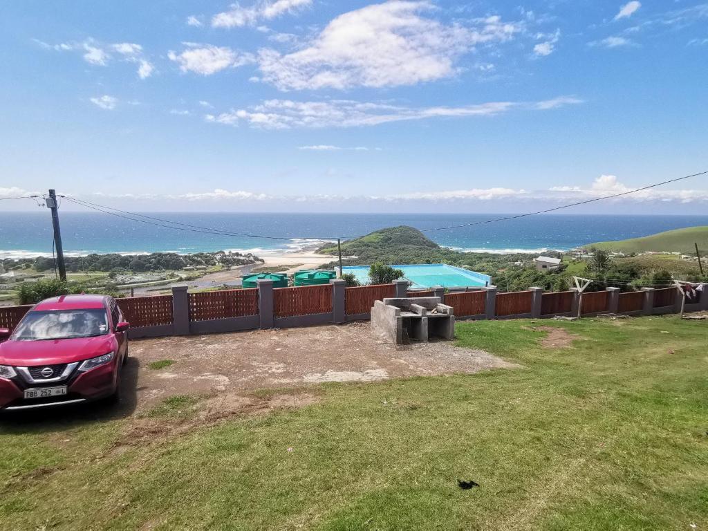 a car parked in a yard with a view of the ocean at Hillside View Guesthouse in Coffee Bay