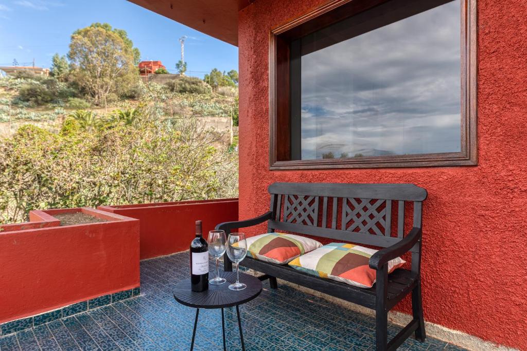 a bench on a porch with a window and wine glasses at El Jardin de Santa Brígida with private pool, sauna & jacuzzi in Santa Brígida