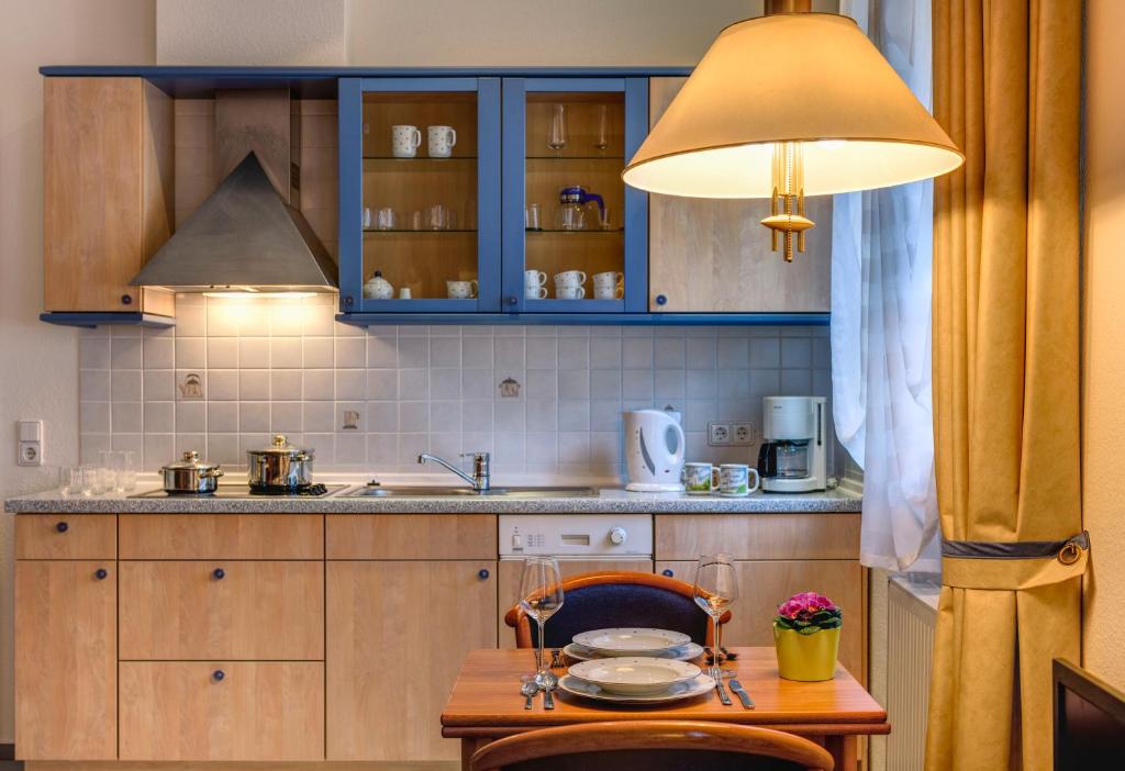 a kitchen with blue cabinets and a wooden table at Hotel Aquamarin in Kühlungsborn