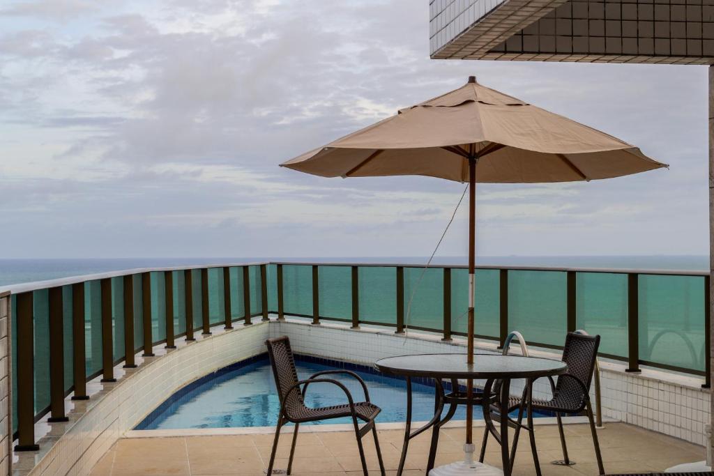 a table and chairs with an umbrella on a balcony at Apartamento Jussara Freitas 2 quartos in Recife