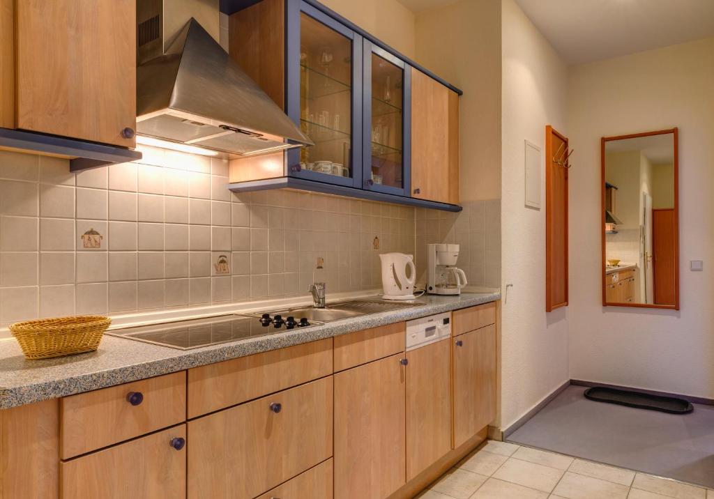 a kitchen with wooden cabinets and a sink at Hotel Aquamarin in Kühlungsborn