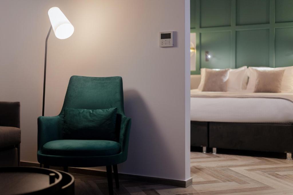 a green chair in a room with a bed at The Embassy Valletta Hotel in Valletta