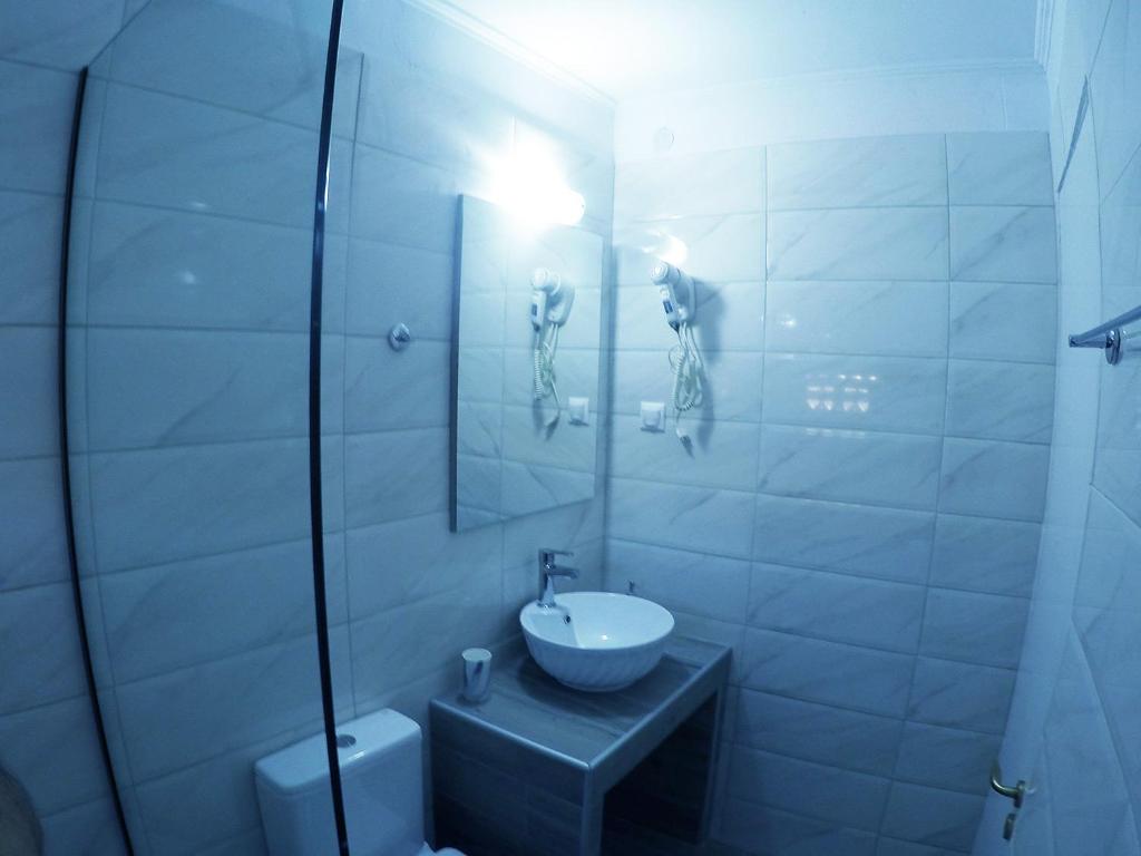uma casa de banho branca com um lavatório e um espelho em Zacharogianni Studios em Nikiana