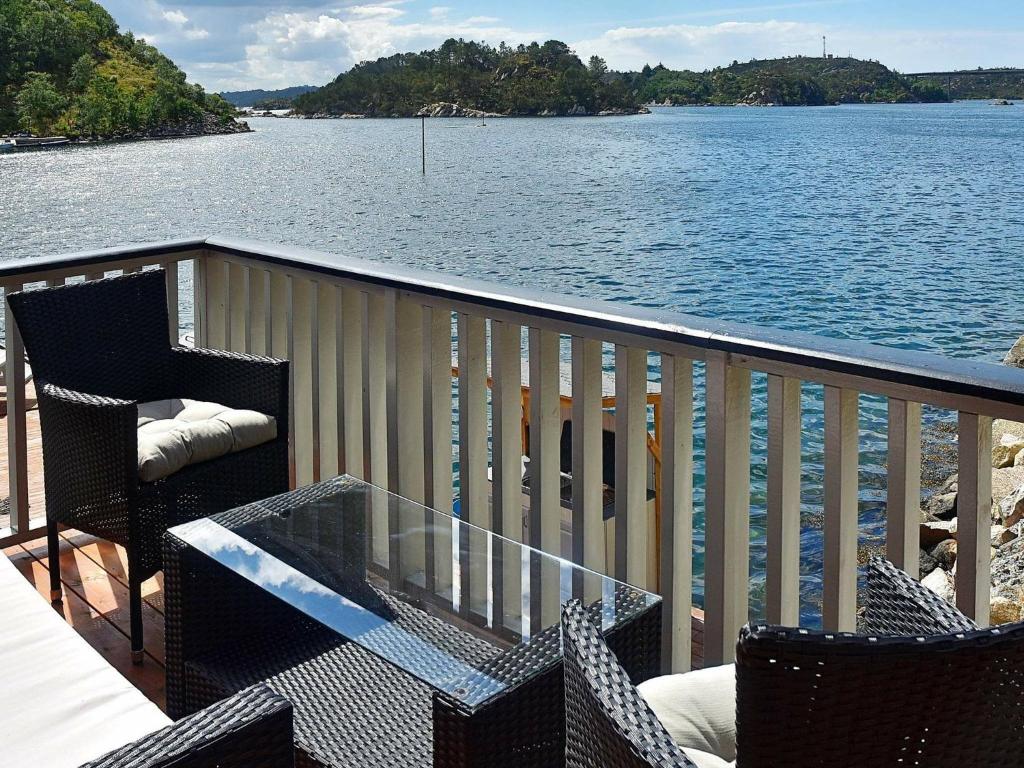 a balcony with a glass table and chairs next to the water at 4 person holiday home in Urangsv g in Ervik
