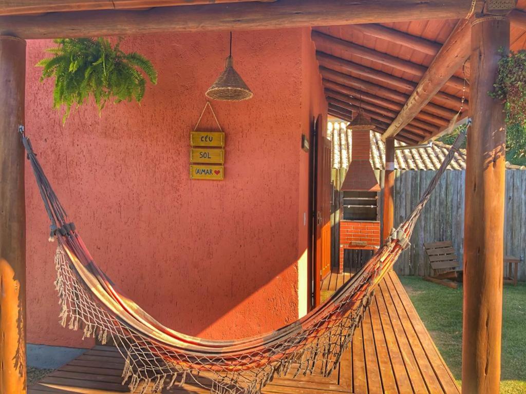 a hammock in front of a house with a porch at Luz da Lua Cabanas Comfort in Praia do Rosa