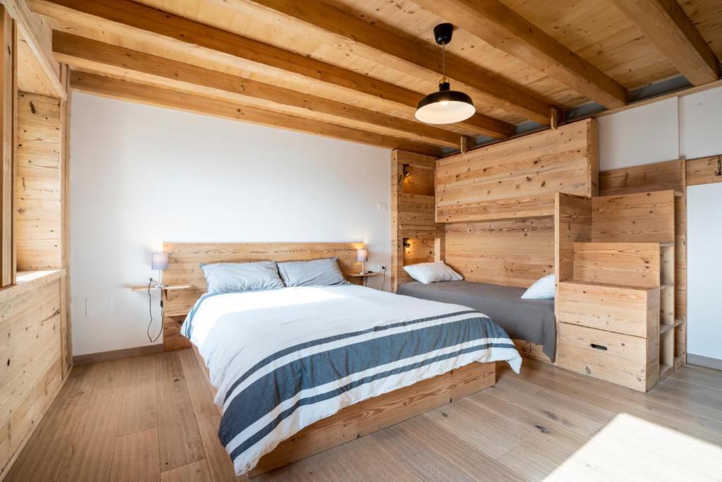 a bedroom with a large bed and wooden walls at Casa Ekharle - Affittacamere in Rotzo