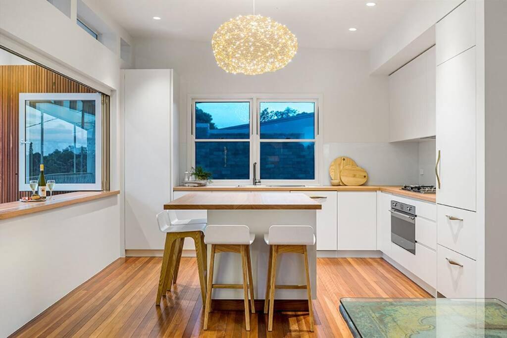 a kitchen with white cabinets and a counter with stools at The Terrace Penthouse Apartment in Brunswick Heads