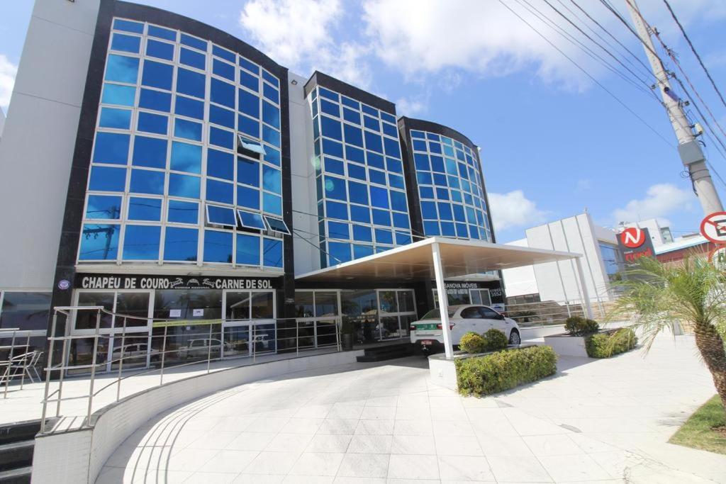 een groot glazen gebouw met een auto ervoor geparkeerd bij Imperial Flat in João Pessoa