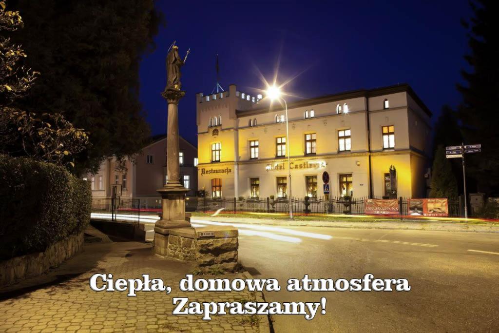 un edificio con una estatua delante de él por la noche en Hotel i Restauracja Castle, en Bystrzyca Kłodzka