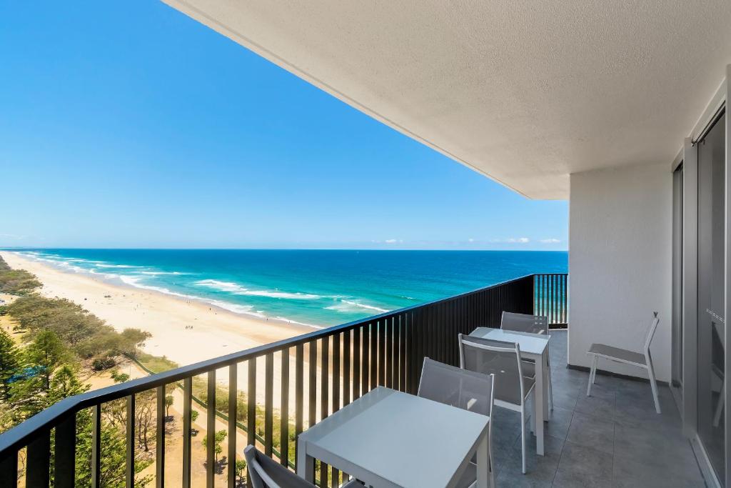 a balcony with tables and chairs and the beach at Golden Sands on the Beach - Absolute Beachfront Apartments in Gold Coast