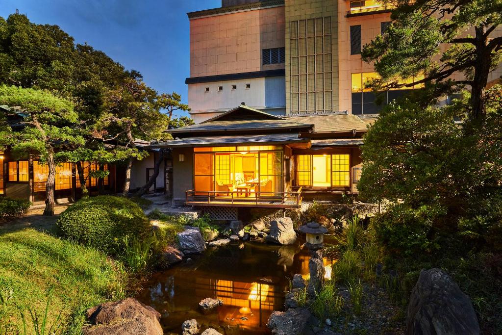 een huis met een vijver voor een gebouw bij Suisui Garden Ryokan (in the Art Hotel Kokura New Tagawa) in Kitakyushu