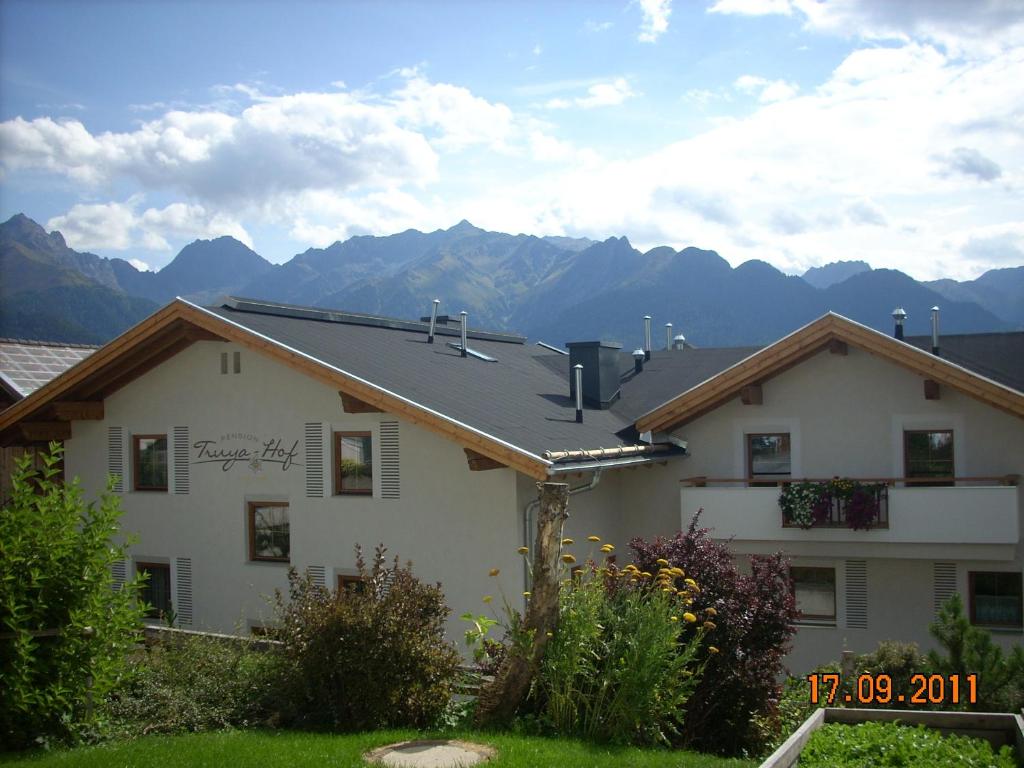 a white house with mountains in the background at Pension Truya - Hof in Fiss