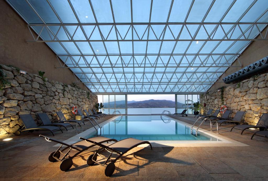 una piscina con sillas y un gran techo de cristal en Parador de Lorca, en Lorca