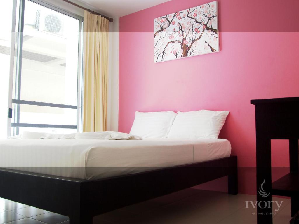 a bed in a room with a pink wall at Ivory Phi Phi Island in Phi Phi Don