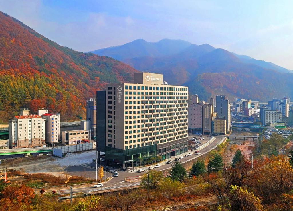 a large building in a city with mountains in the background at Jeongseon Intoraon Hotel in Jeongseon