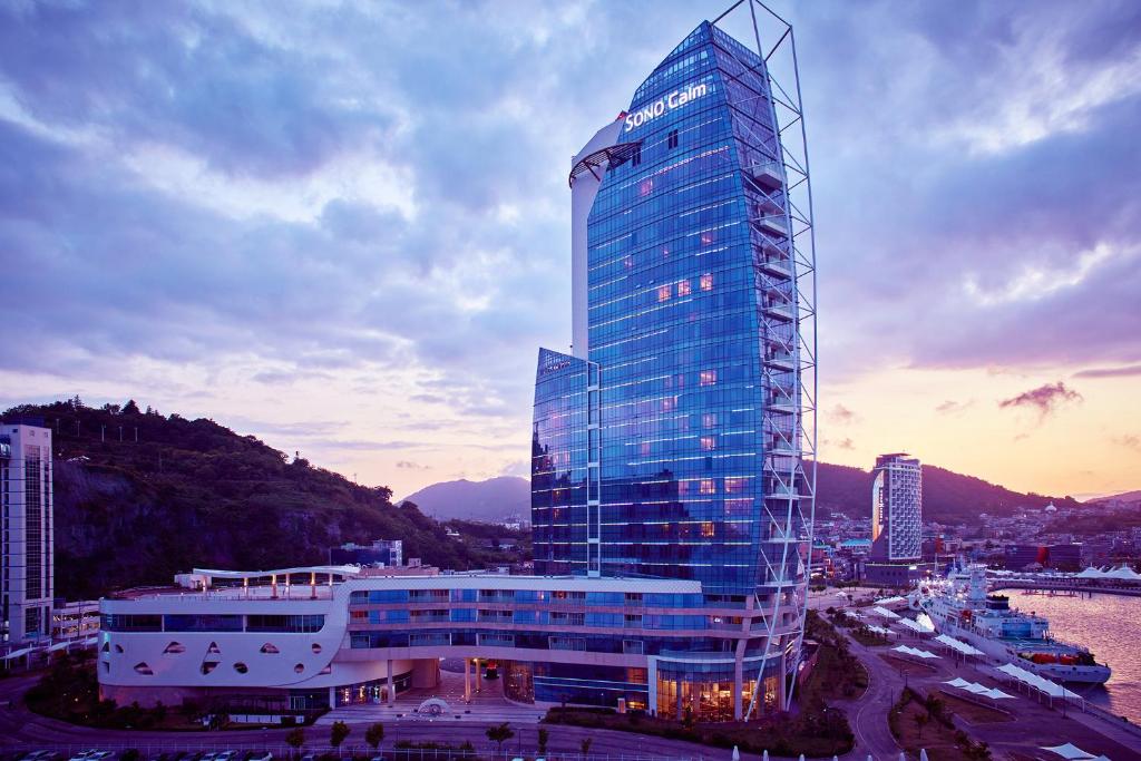 a tall glass building in a city with a harbor at Sono Calm Yeosu in Yeosu