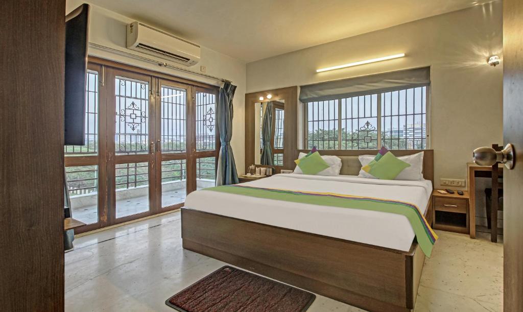 a bedroom with a large bed and windows at Treebo Trend Sreemaa Newtown in Pānchuria