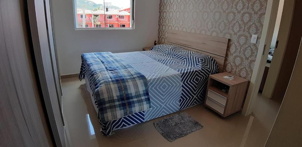 Habitación pequeña con cama y mesita de noche en Lindo apartamento, todo novo en Florianópolis