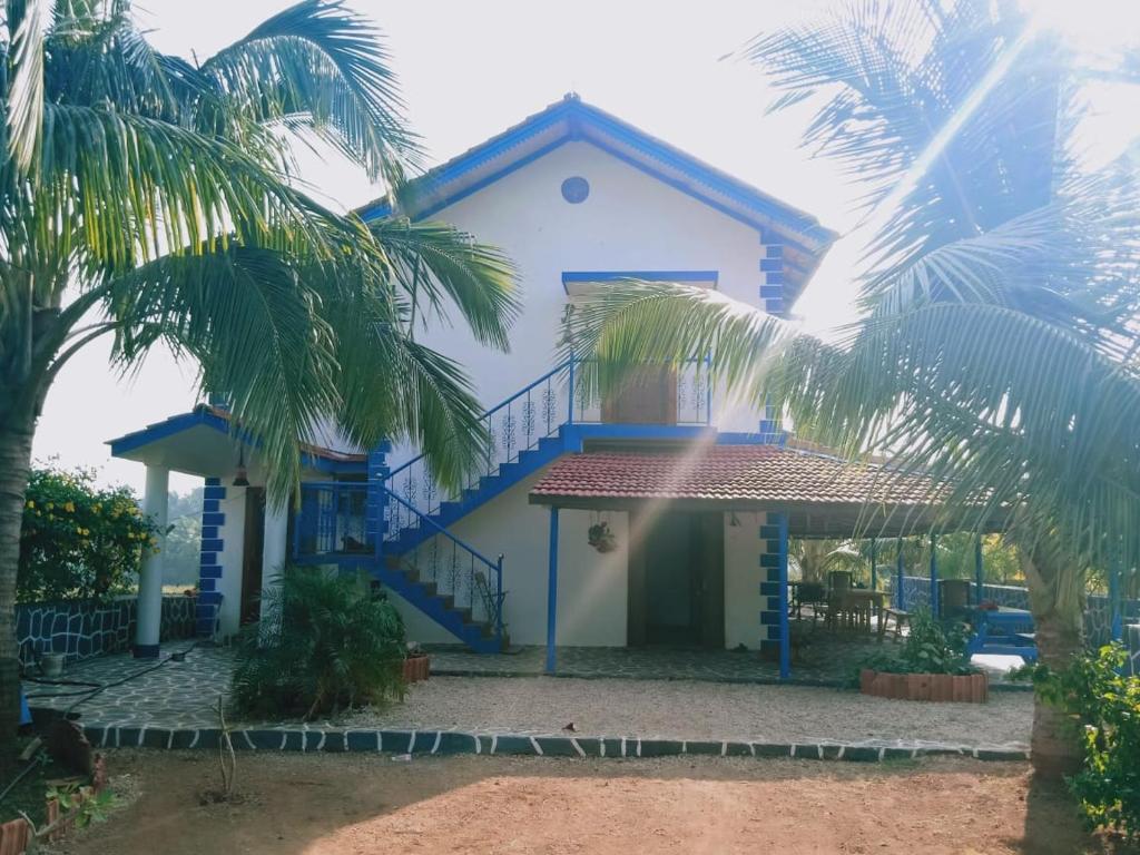 a blue and white house with palm trees at Aqua Arina Holiday Farm House in Murud