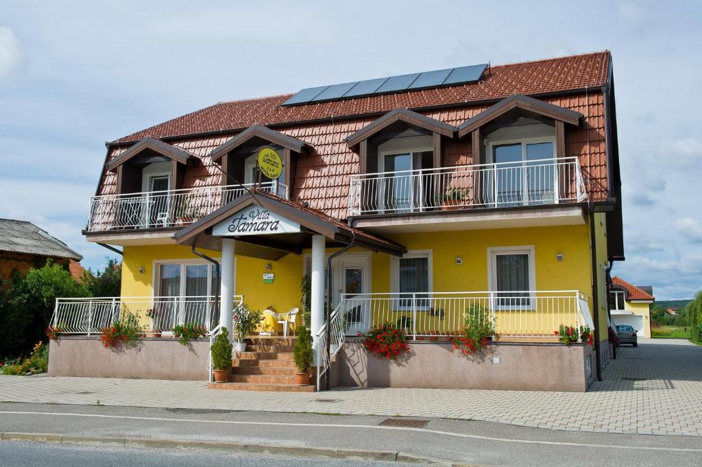 una casa amarilla con balcones en una calle en Garni Hotel Villa Tamara, en Moravske Toplice