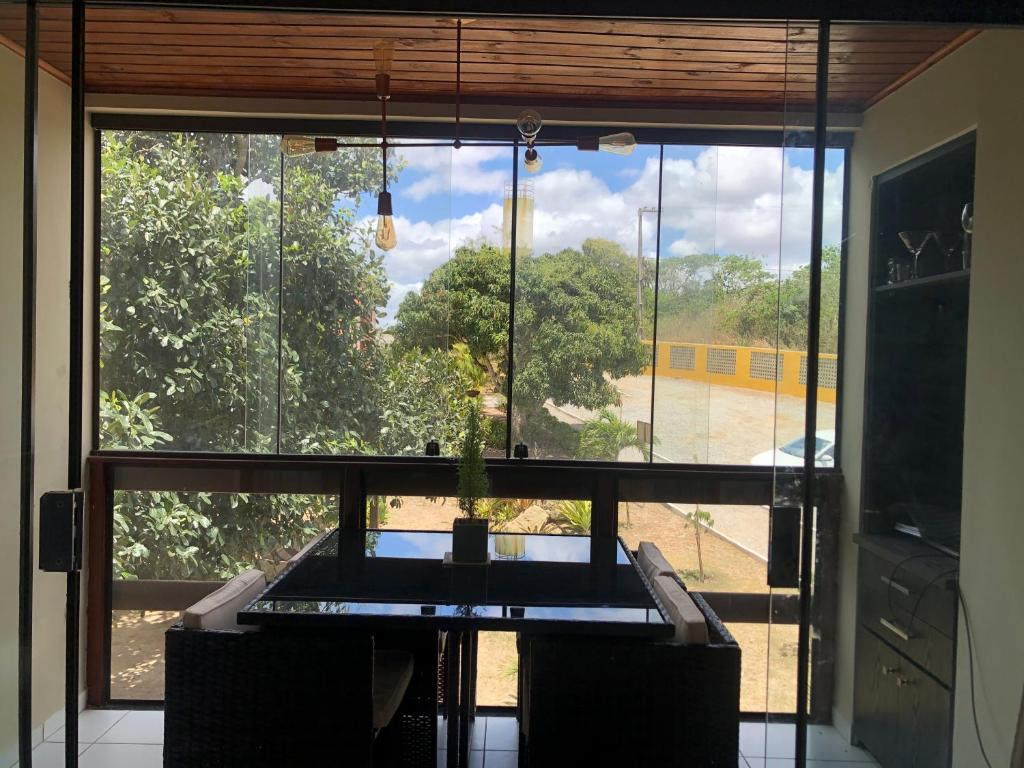Flat no Condomínio Paraíso Serra Negra - A 200m da Bodega de Véio في بيزيروس: غرفة مع نافذة كبيرة مع طاولة وكراسي
