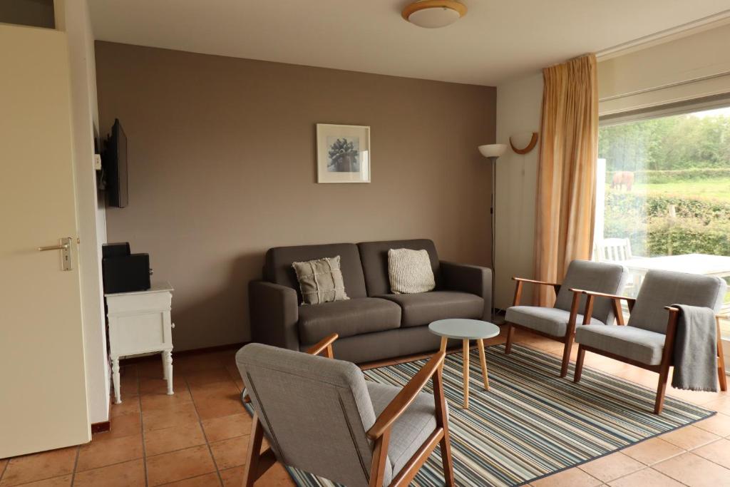 een woonkamer met een bank, stoelen en een tafel bij Vakantiewoningen Ons Krijtland in Epen