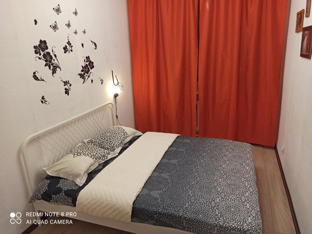 1 dormitorio con cama y cortina roja en Apartment Pavlyukhina 100 en Kazán
