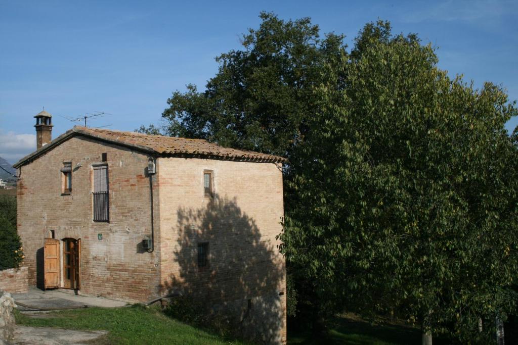 un viejo edificio de ladrillo con un árbol al lado en Cal Cisteller, en Gironella