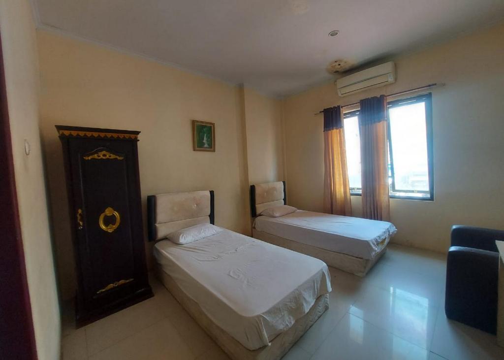 a small room with two beds and a window at Hotel Mulia Kendari Mitra RedDoorz in Pipulu