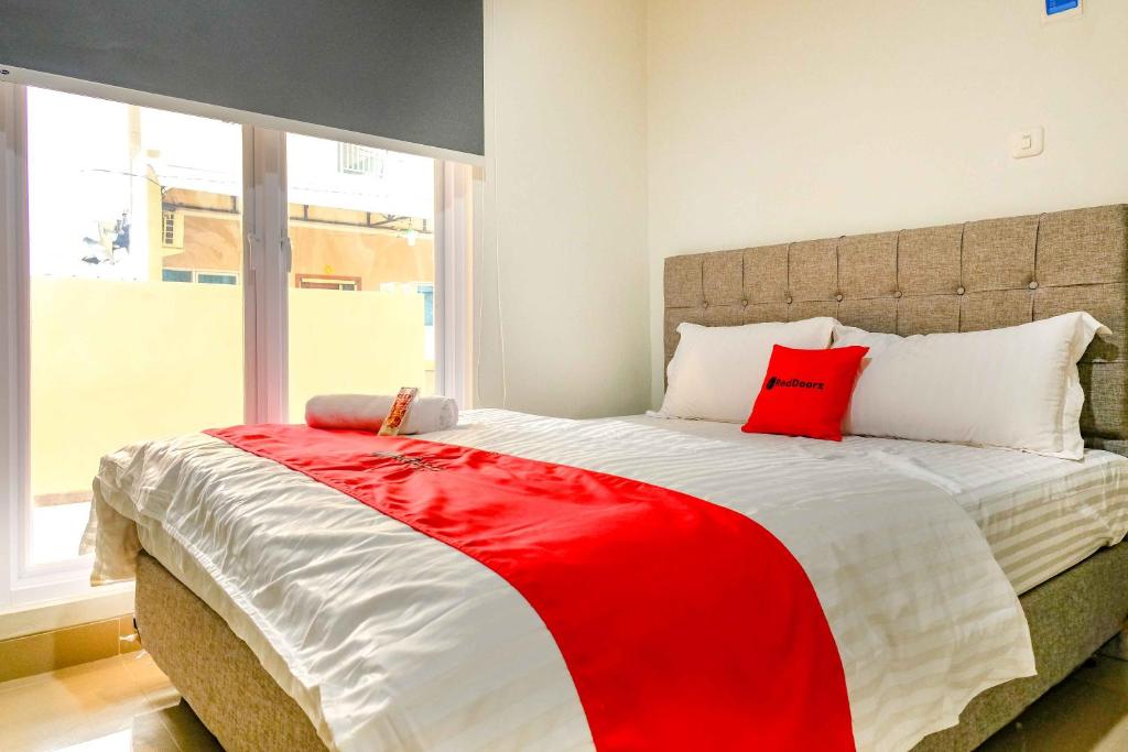 a bedroom with a large bed with a red pillow at RedDoorz near Pasar Baru 3 in Jakarta
