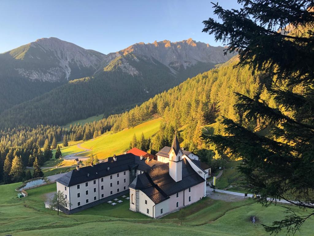 un grand bâtiment sur une colline avec des montagnes en arrière-plan dans l'établissement Maria Waldrast, à Matrei am Brenner