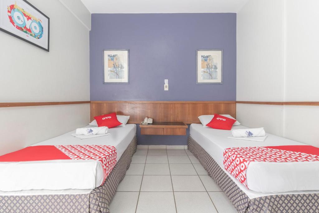 two beds in a hotel room with red pillows at Mangabeiras Hotel in Goiânia