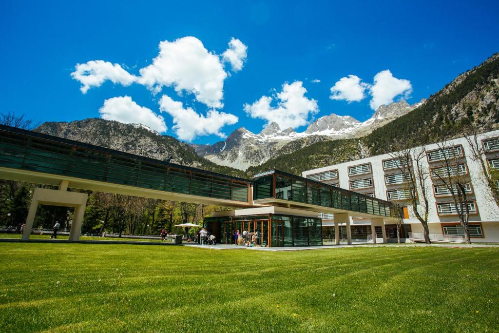 a building with a grassy field in front of a mountain at Hotel Continental Balneario de Panticosa in Panticosa