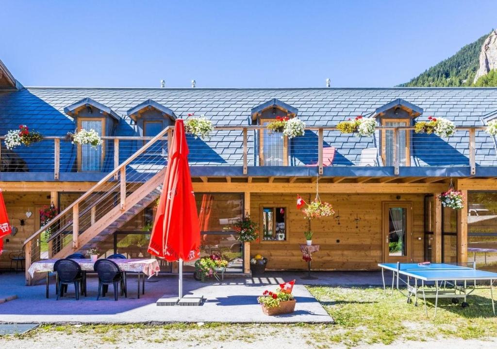 a log cabin with tables and umbrellas in front of it at Bnb la Péniche in Evolène