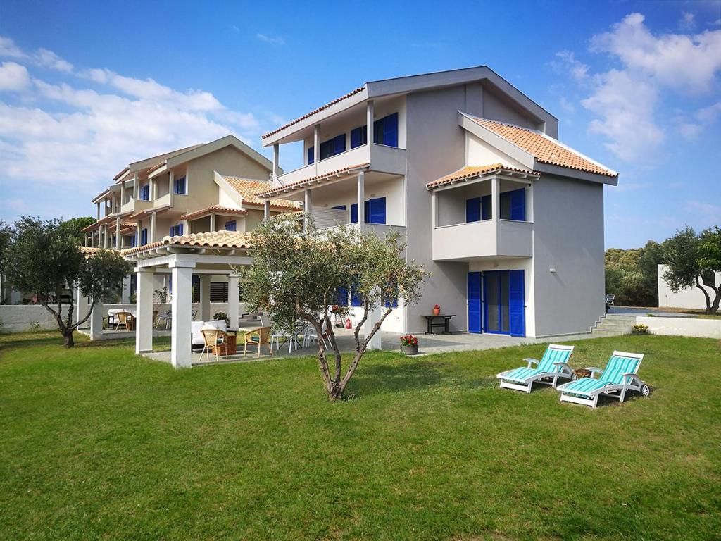 a large house with two chairs in a yard at Olive Bay Hilltop Apartments Ammouliani in Ammouliani