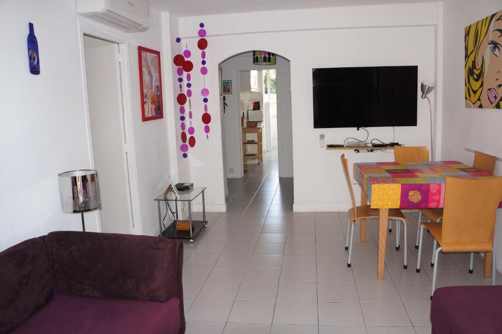 a living room with a table and a tv at Appartement T3 Climatisé entre mer et centre Nice in Nice