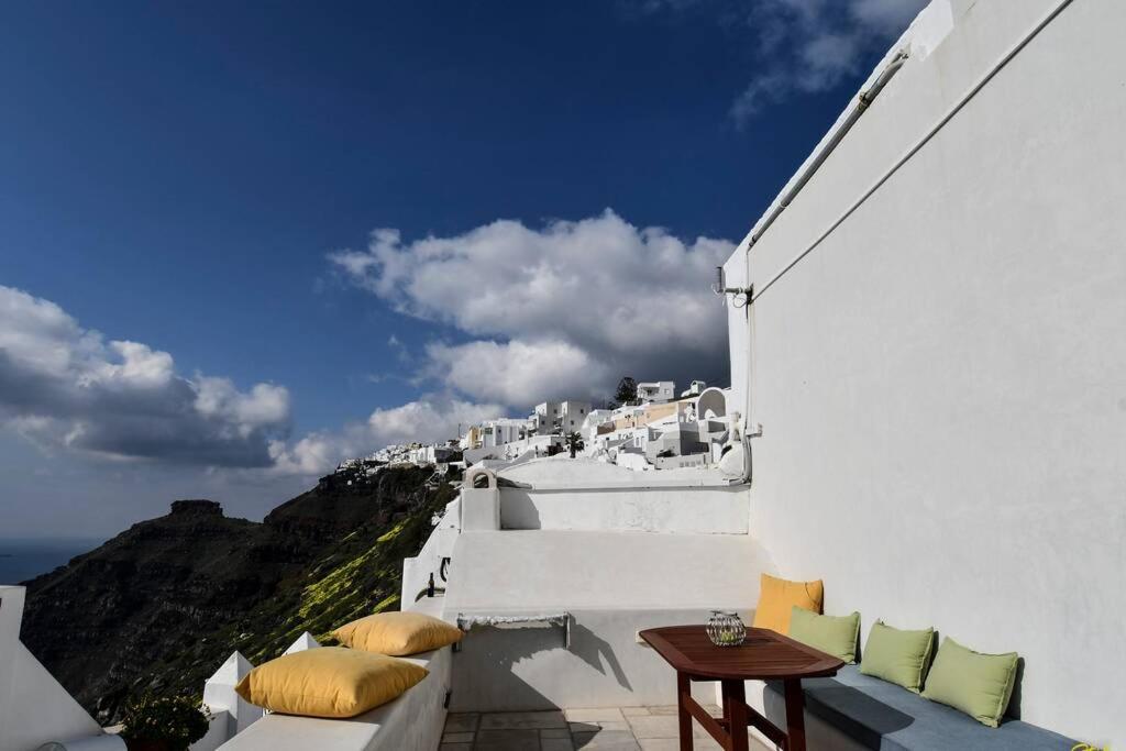 a balcony with a table and a view of the ocean at Stefani Cave House Santorini in Firostefani