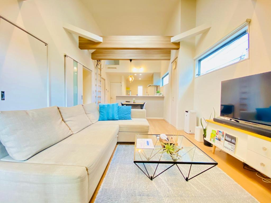 a living room with a white couch and a flat screen tv at AddressHokancho in Okayama