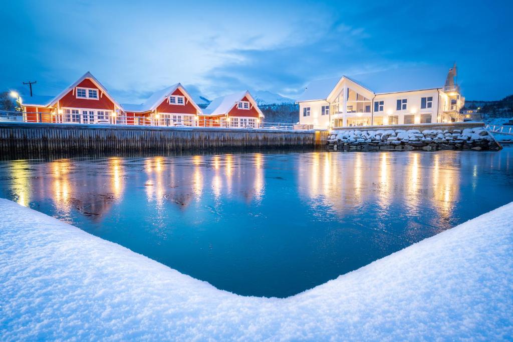 una fila de casas en un muelle en la nieve en Senja Fjordhotell and Apartments, en Stonglandseidet