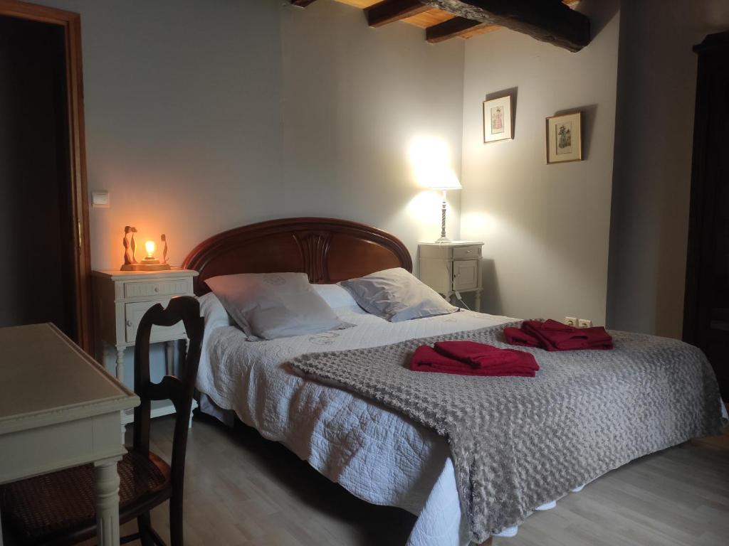 1 dormitorio con 1 cama con 2 toallas rojas en Les chambres de la Caussade, en Lautrec