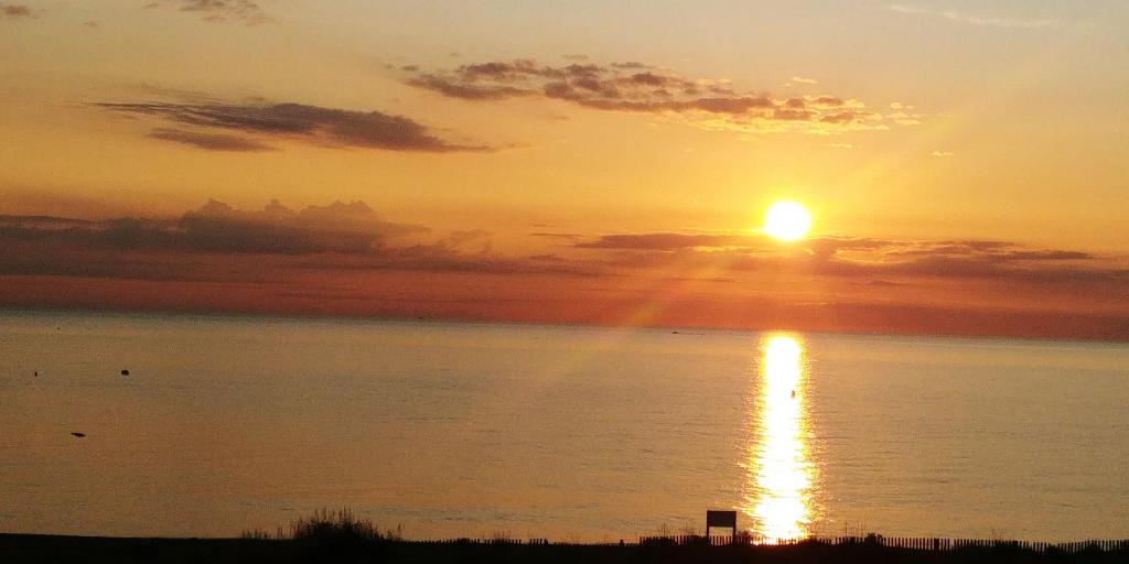 a sunset over the water with the sun in the sky at Vue Mer Panoramique WIFI gratuit in Le Barcarès