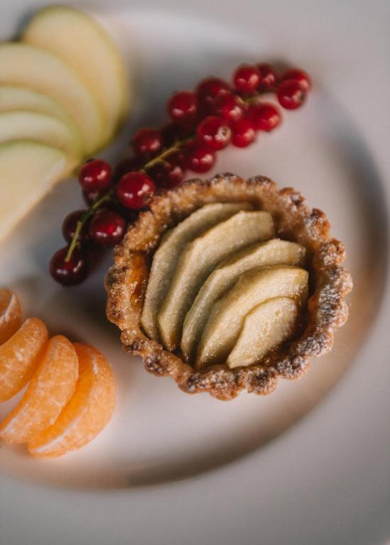 a plate with a pie and fruit on it at Mami Sabaudia Hotel in Sabaudia