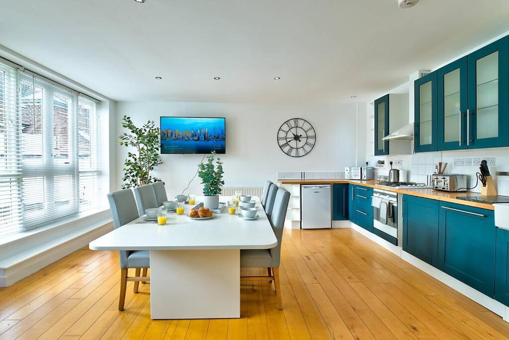 a kitchen with a white table and blue cabinets at School Path Ironbridge Townhouse with Roof Terrace in Ironbridge